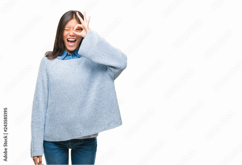 Young asian woman wearing winter sweater over isolated background doing ok gesture with hand smiling, eye looking through fingers with happy face. Young asian woman wearing winter sweater over isolated background doing ok gesture with hand smiling, eye looking through fingers with happy face.