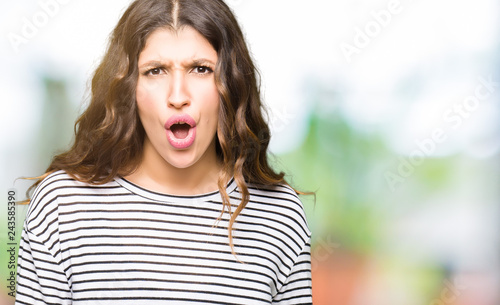Young beautiful woman wearing stripes sweater afraid and shocked with surprise expression, fear and excited face.