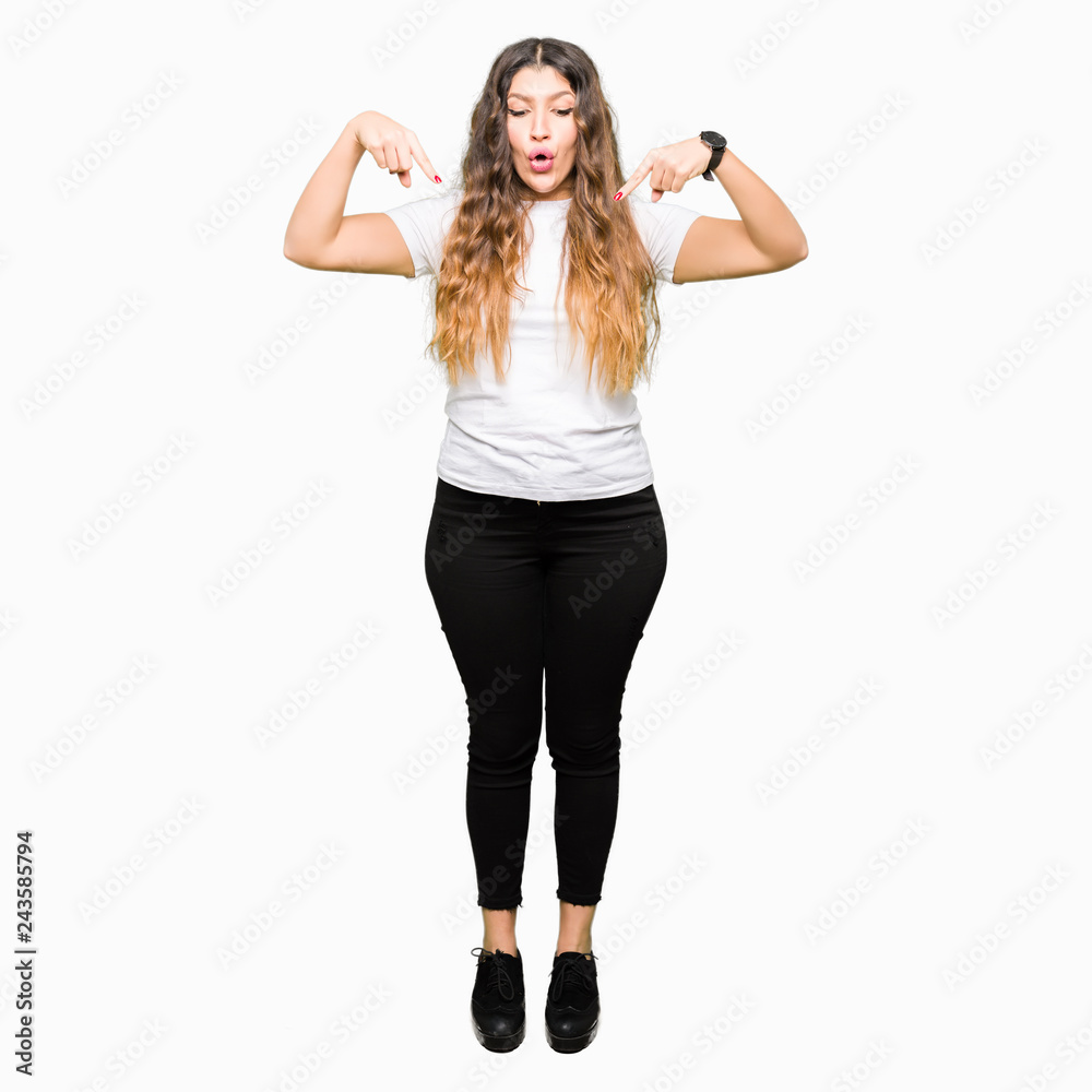 Young beautiful woman wearing casual white t-shirt Pointing down with fingers showing advertisement, surprised face and open mouth Young beautiful woman wearing casual white t-shirt Pointing down with fingers showing advertisement, surprised face and open mouth