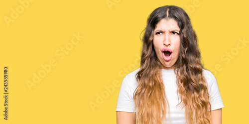 Young beautiful woman wearing casual white t-shirt In shock face, looking skeptical and sarcastic, surprised with open mouth