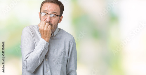Handsome middle age elegant senior man wearing glasses over isolated background looking stressed and nervous with hands on mouth biting nails. Anxiety problem.