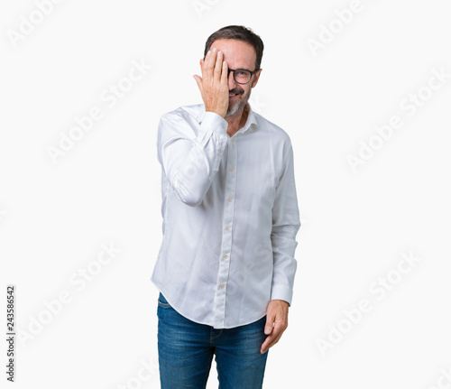 Handsome middle age elegant senior business man wearing glasses over isolated background covering one eye with hand with confident smile on face and surprise emotion.