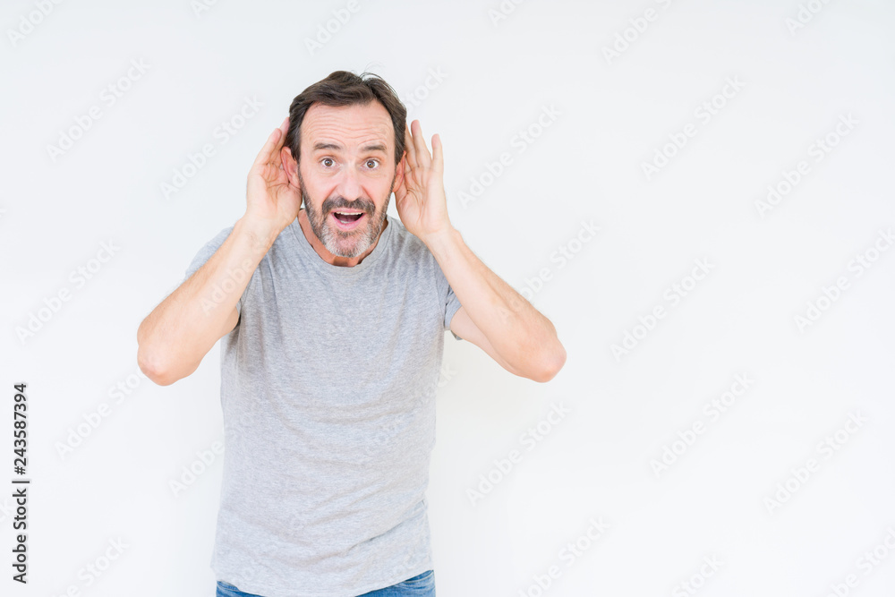 Fototapeta premium Handsome senior man over isolated background Trying to hear both hands on ear gesture, curious for gossip. Hearing problem, deaf