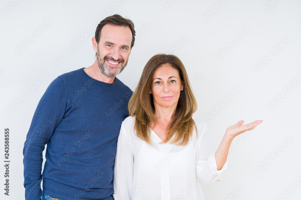 Beautiful middle age couple in love over isolated background smiling cheerful presenting and pointing with palm of hand looking at the camera. Beautiful middle age couple in love over isolated background smiling cheerful presenting and pointing with palm of hand looking at the camera.