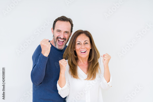 Beautiful middle age couple in love over isolated background celebrating surprised and amazed for success with arms raised and open eyes. Winner concept.