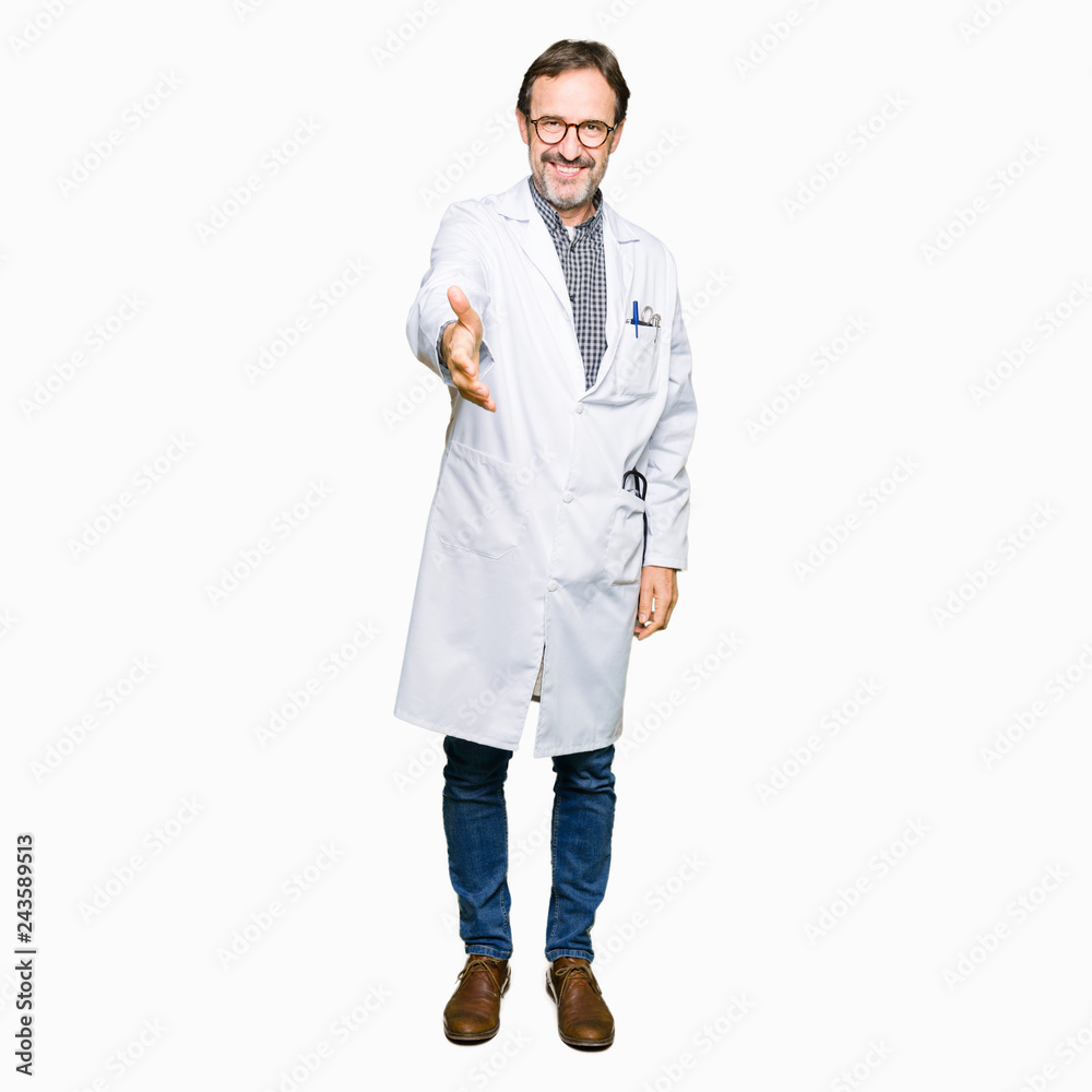 Middle age doctor men wearing medical coat smiling friendly offering handshake as greeting and welcoming. Successful business.