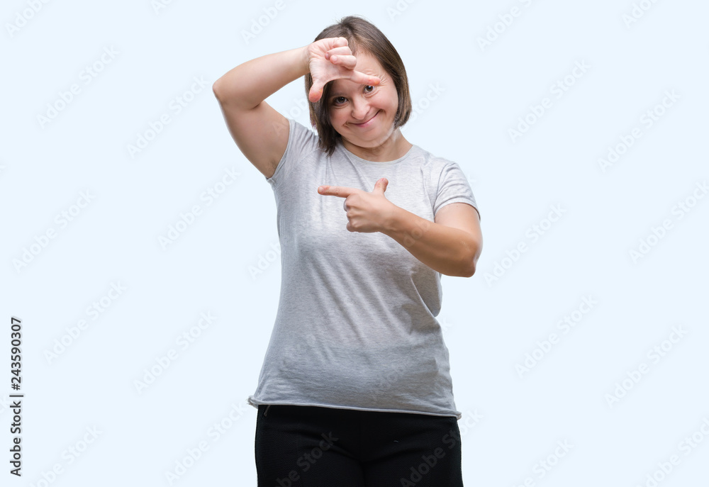Young adult woman with down syndrome over isolated background smiling making frame with hands and fingers with happy face. Creativity and photography concept.