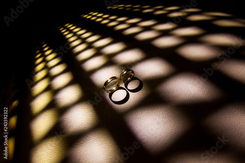 Alianças de noivos no dia do casamento, iluminada por uma luz quadriculada, formando uma luz diagonal