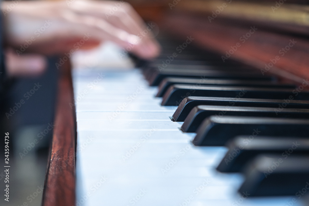 Closeup image of hands playing a vintage wooden grand piano