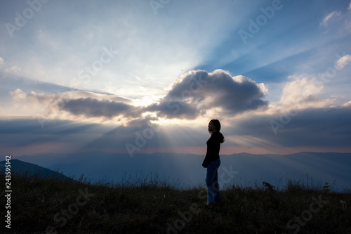 A woman standing and watching sunset with mountains view in the evening