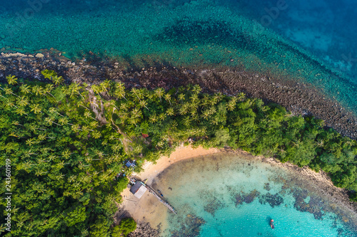 Aerial view of exotic turquoise sea with white beach green tree island