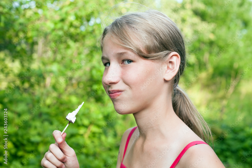 smiling teen girl with chocolate popsicle ice cream in the hand on green outdoor background smiling teen girl with chocolate popsicle ice cream in the hand on green outdoor background