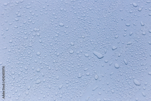 Wet rain drops on silver car hood. Abstract background. Water drops on red metal texture. Shallow focus, car body. Detail of red wet surface after rain 