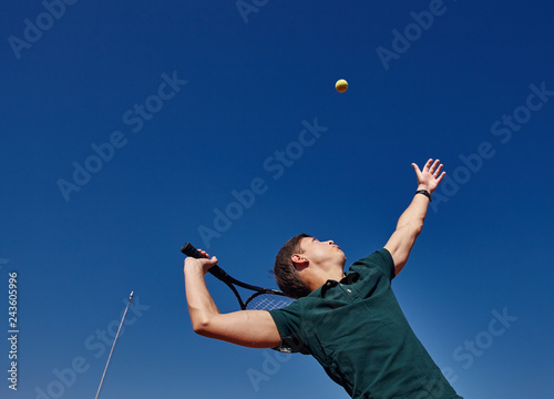 a Man playing tennis on the court on a beautiful sunny day © shyshka