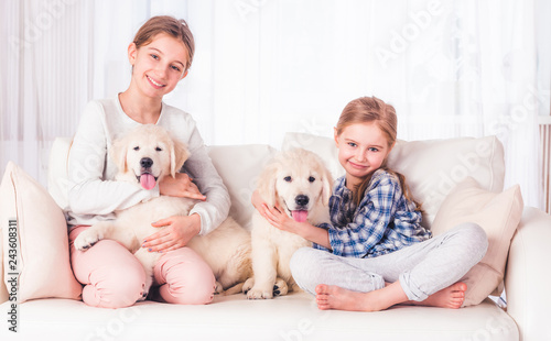 Smiling sisters sitting with puppies