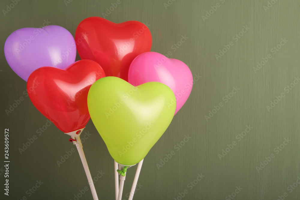A group of colorful heart shaped ballons against green chalkboard