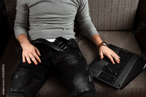 Fotografi A man watches an adult video on a laptop while sitting on the couch