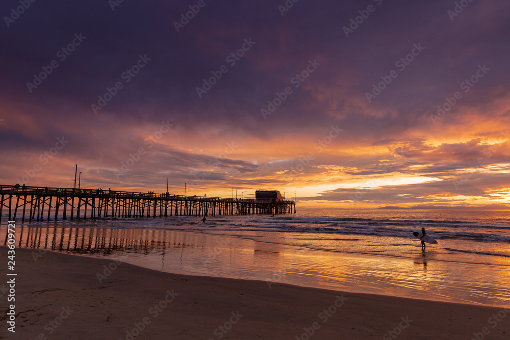 surfer and pier with beautiful sunset