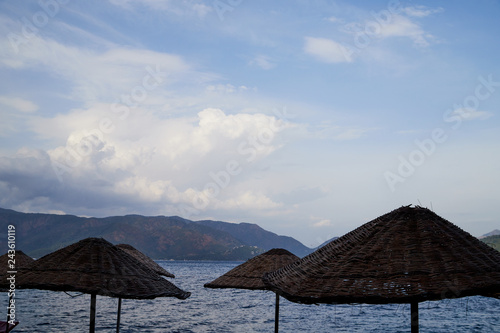 Sea  mountain and braided umbrellas in a summer day