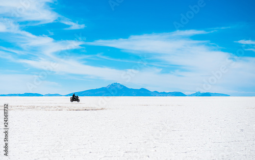 Sunshine scenery of Salar de Uyuni in Bolivia with biker riding over