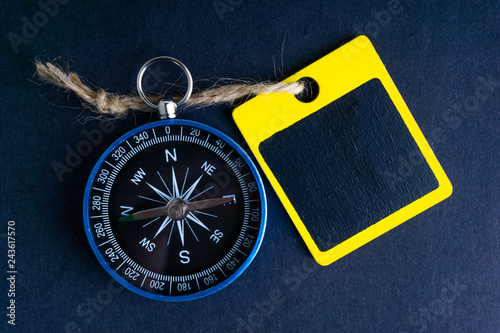 Wooden tag and compass on black background with selective focus and crop fragment. Business and motivation concept