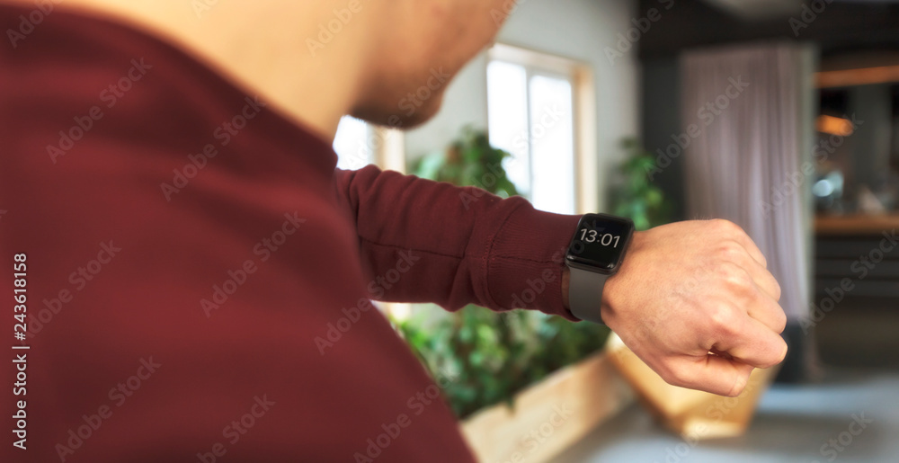 The man  is looking on his smart watches on his hand