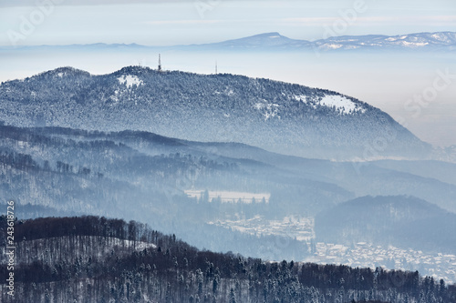 Winter scenery with misty valleys at the base of Tampa mountain near Brasov city, Romania.