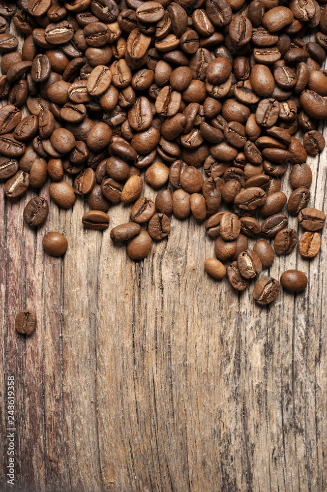 Naklejka premium Pile of roasted coffee beans on wood