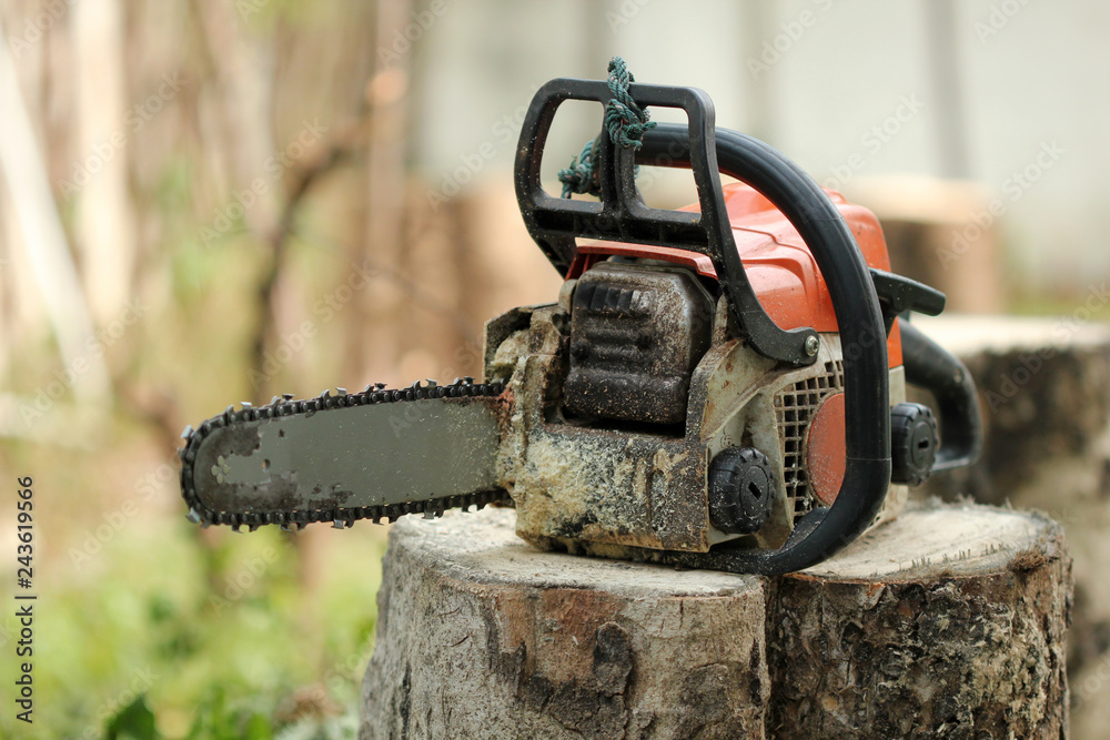 Portable chainsaw machine with sawdust line on wood stump banner on blur background. Heavy duty wood cutting equipment