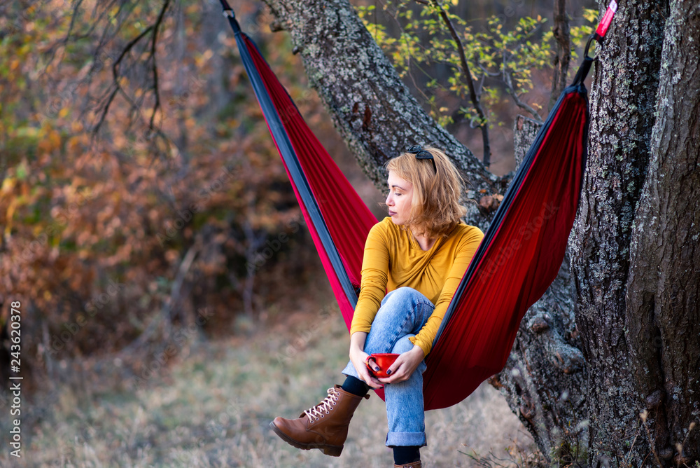 Woman sitting in a hammock with a cup of coffee Woman sitting in a hammock with a cup of coffee