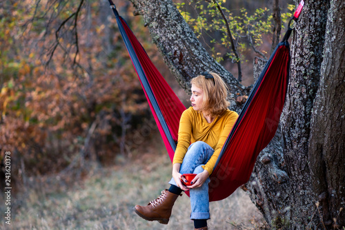 Woman sitting in a hammock with a cup of coffee