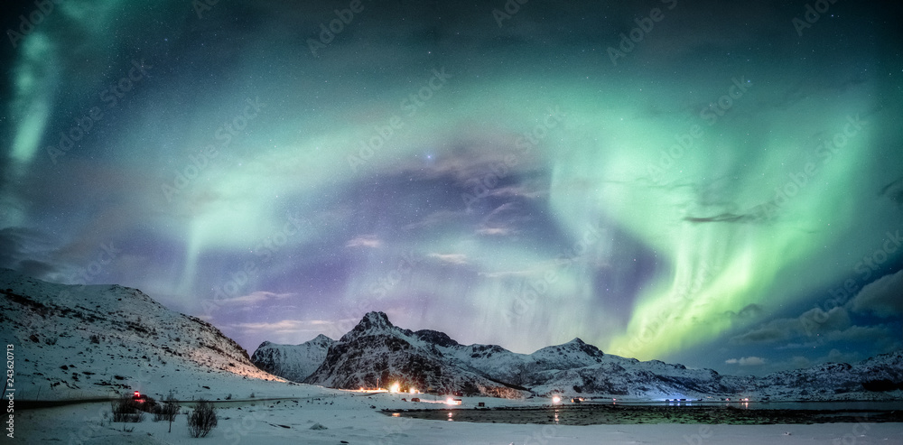 Northern lights explosion on snowy mountain range - obrazy, fototapety, plakaty 