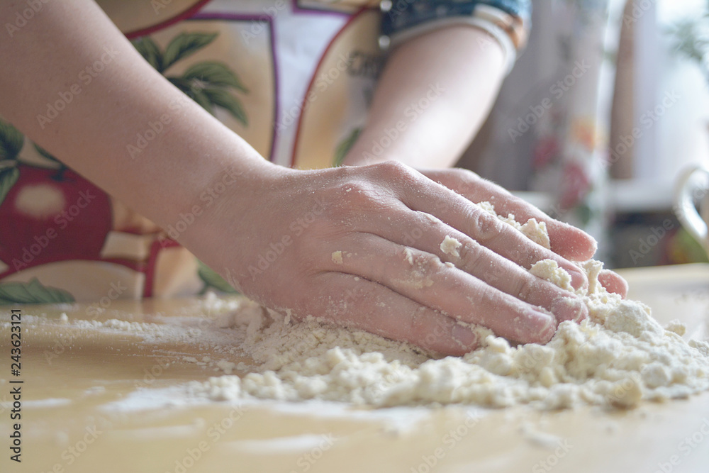 A woman in a colored apron kneads dough on the table. A woman in a colored apron kneads dough on the table.