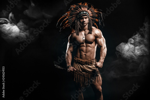 American Indian Apache warrior chief in traditional clothing and feathered headdress with weapon. Indian chieftain of the tribe with muscled strength body with arrows.