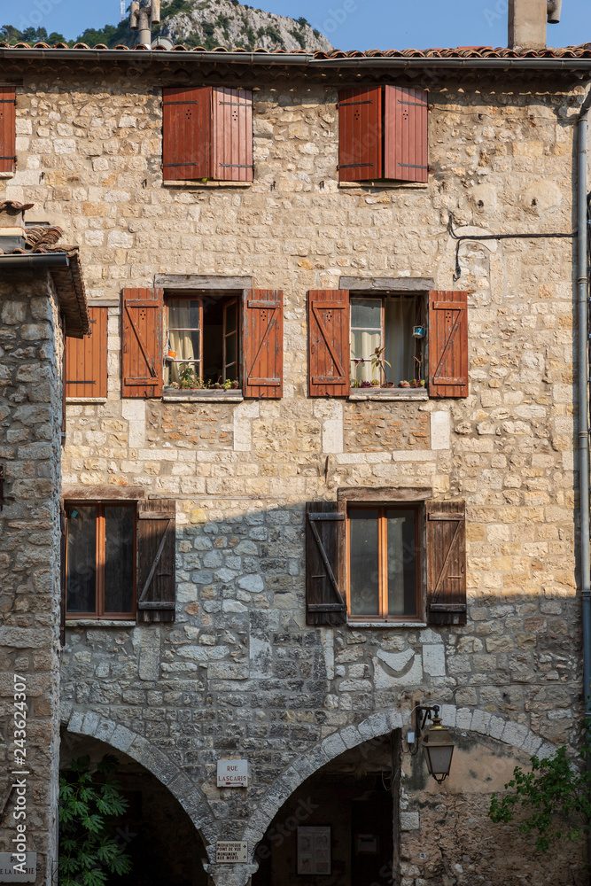 Beautiful stone building with brown shuttered windows in Peille, France