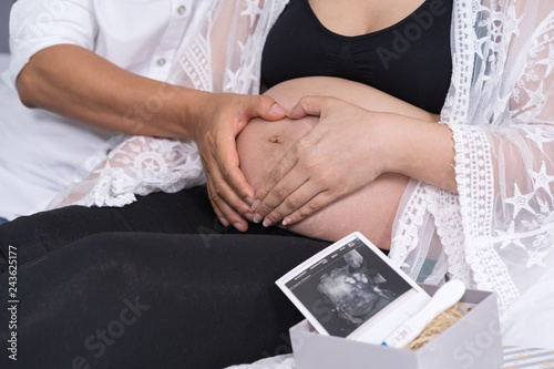 husband and his pregnant wife showing heart with hands