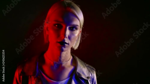 androgynous model with blonde hair is looking forward to camera inside dark room photo