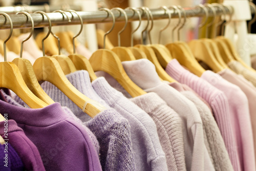 Multicolored knitted sweaters hang on hangers in the store