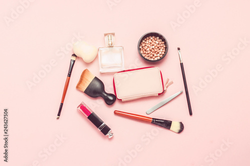 Means for make-up and beauty on a pink background. The concept of face and body care, morning makeup, the contents of a women's bag. Flat lay, top view.