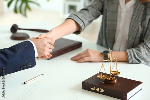 Male lawyer and woman shaking hands in office