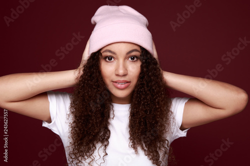 Image of happy young african woman standing isolated over pink background wearing warm scarf. Looking camera