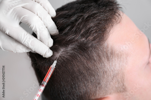 Man with hair loss problem receiving injection in clinic, closeup