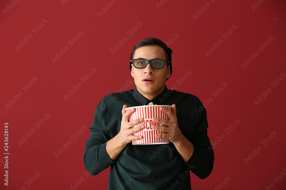 Scared young man with popcorn watching movie on color background Scared young man with popcorn watching movie on color background