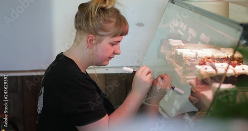 Woman Writing the Prices of Cakes on the Glass