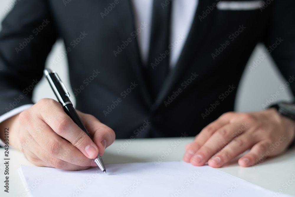 Closeup of executive manager writing on sheet of paper in office. Business man sitting and working at office desk. Paperwork and entrepreneurship concept. Cropped front view. Closeup of executive manager writing on sheet of paper in office. Business man sitting and working at office desk. Paperwork and entrepreneurship concept. Cropped front view.