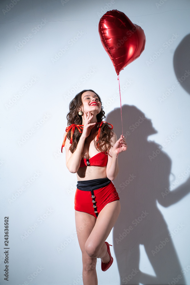 Girl in a red swimsuit, with a ball in the form of a heart near the wall Girl in a red swimsuit, with a ball in the form of a heart near the wall