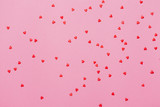 Valentine's day background. Little red hearts on pink background with shining lights bokeh.