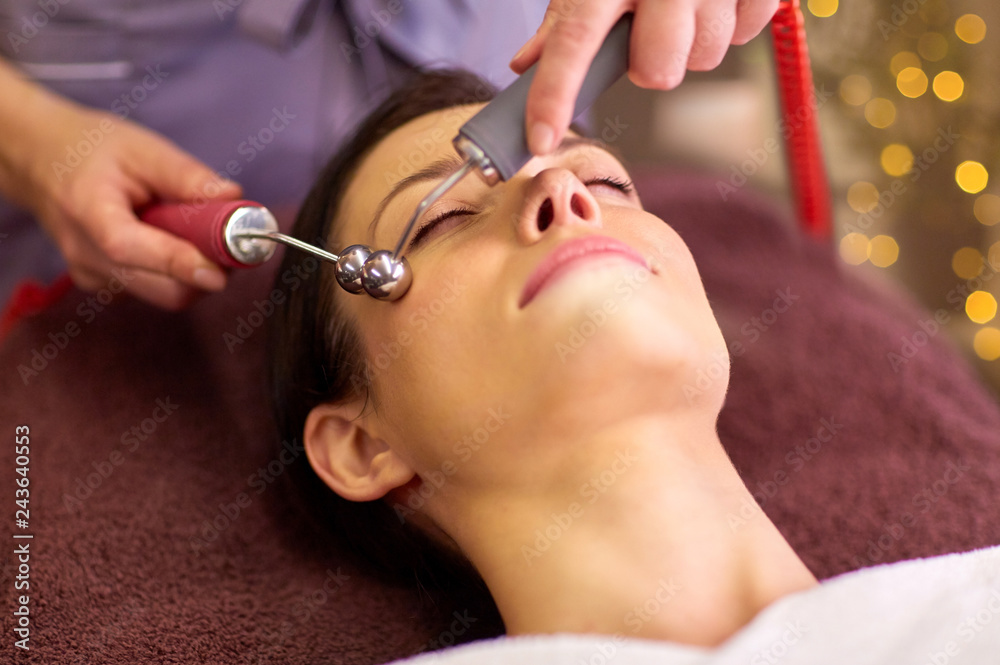 people, beauty, cosmetology and technology concept - beautiful young woman having needle free mesotherapy or hydradermie facial treatment by microcurrent firming device in spa