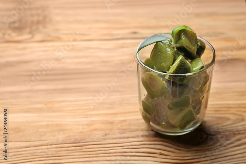 Glass with matcha tea ice cubes on wooden table