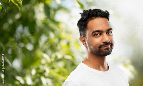 people concept - smiling young indian man over green natural background